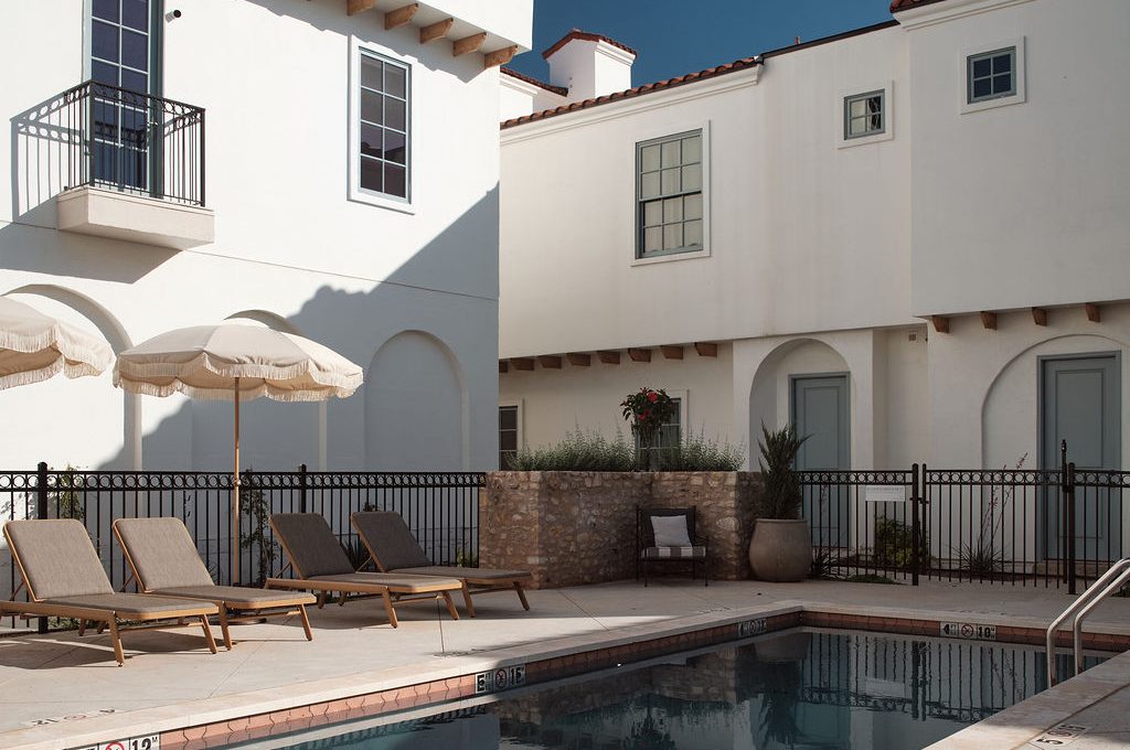 a patio area with a pool, chairs, and a balcony