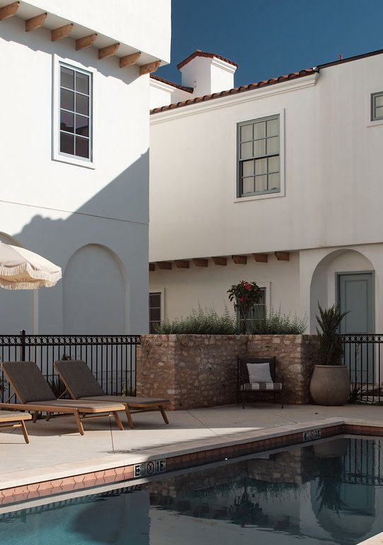 a patio area with a pool, chairs, and a balcony