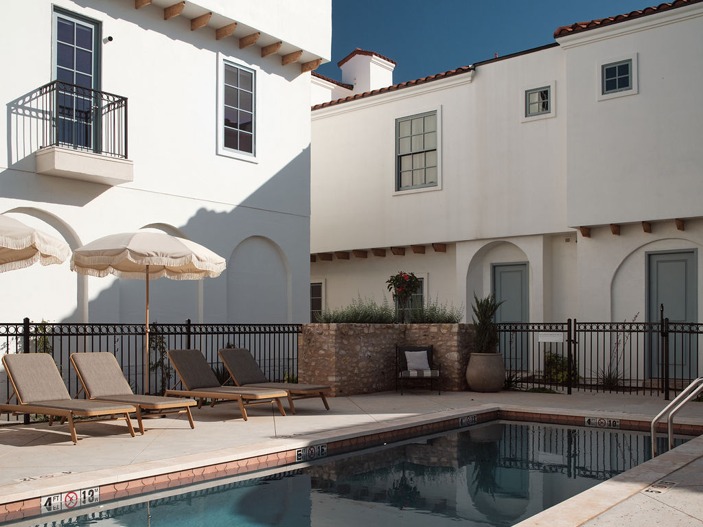 a patio area with a pool, chairs, and a balcony