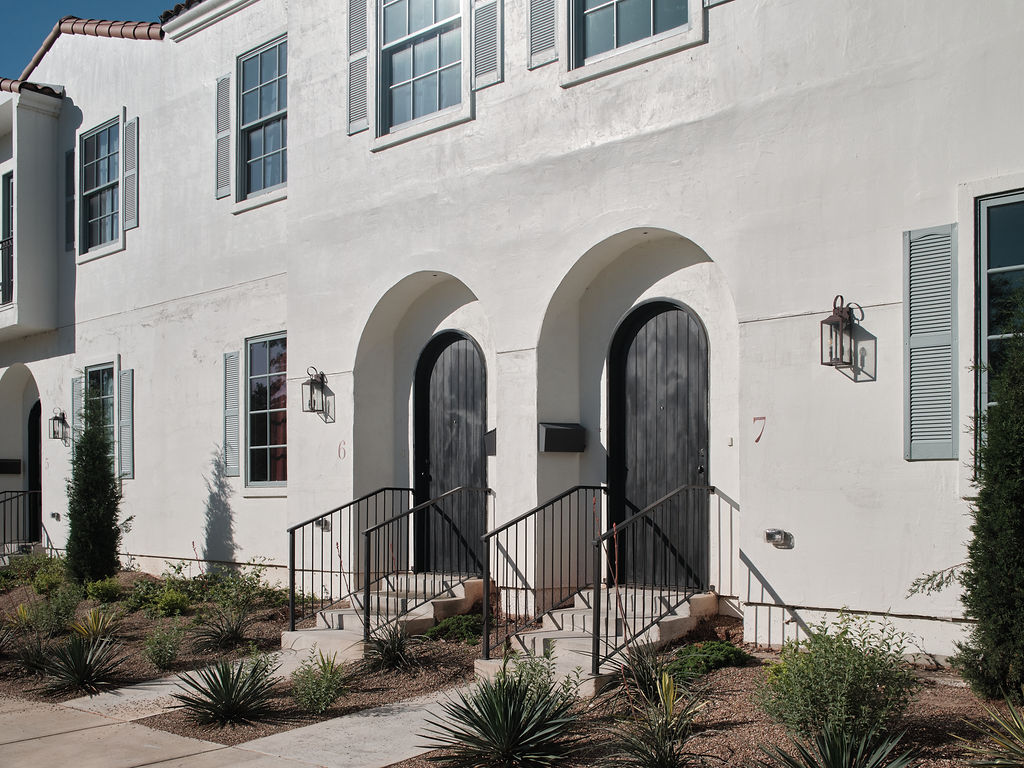 a white building with a black door and a white fence